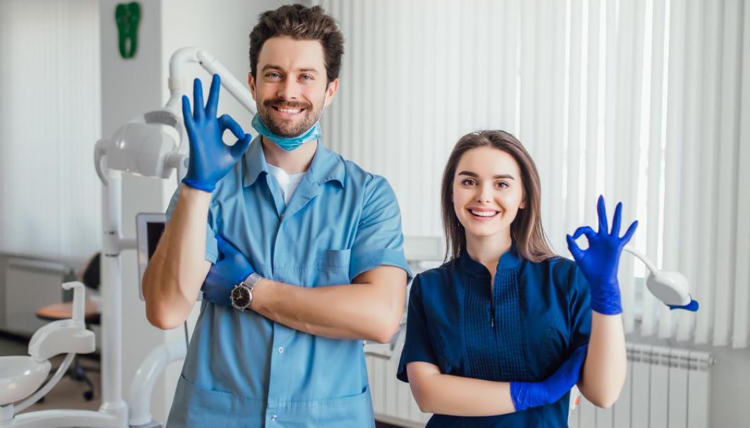 photo-of-smiling-dentist-standing-with-arms-crossed-with-her-colleague-showing-okay-sign.jpg